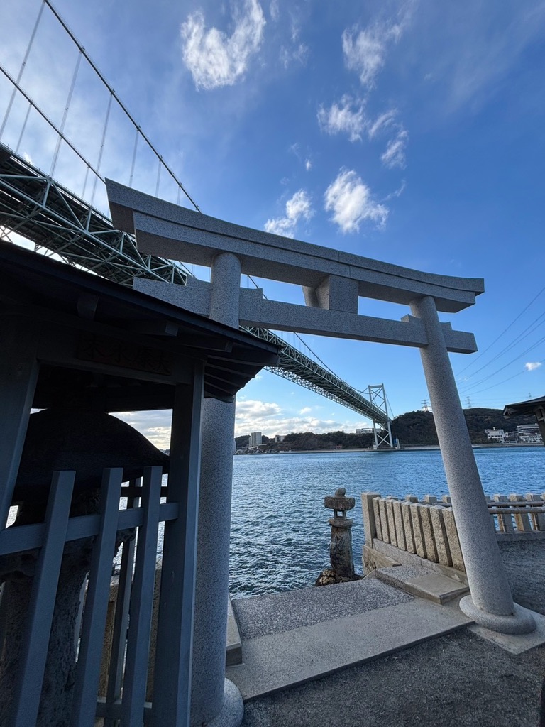 和布刈神社の境内に立つ鳥居と、海際に据えられた石灯籠。背景に関門橋