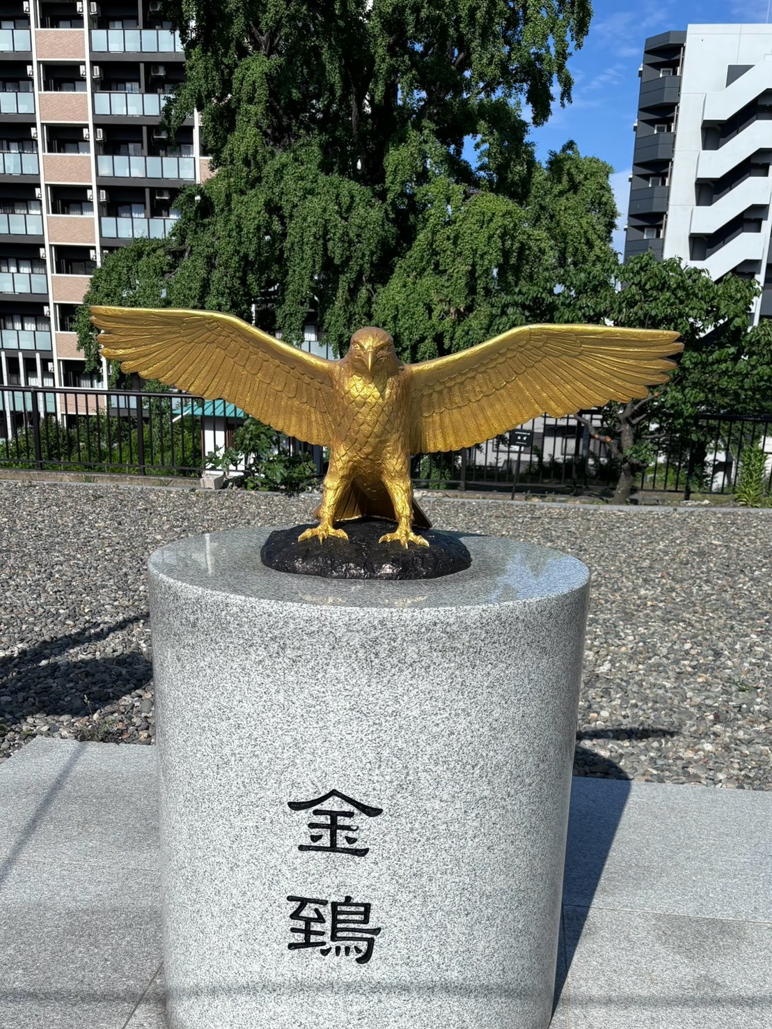 岡田宮の境内に立つ、金色に輝く金鵄(鳶)の銅像。台座に「金鵄」と刻まれている